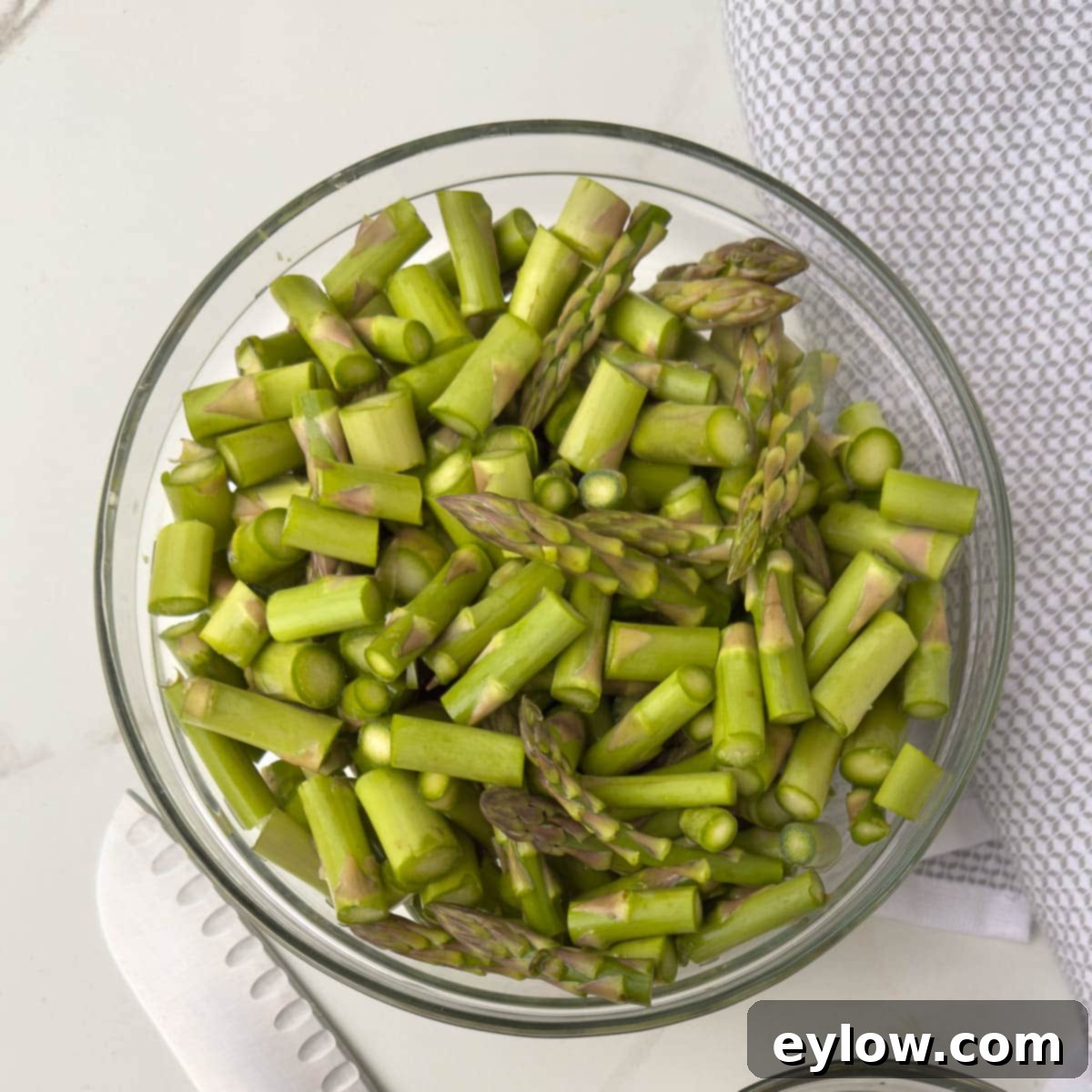 Chopped asparagus spears in a glass bowl, ready for cooking.