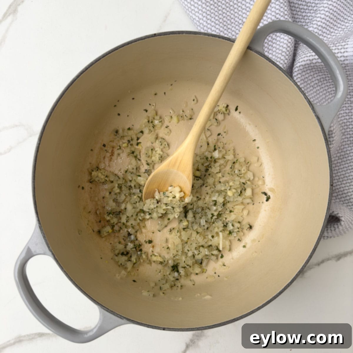 Onion and herbs cooking in a pot, forming the aromatic base for asparagus soup.