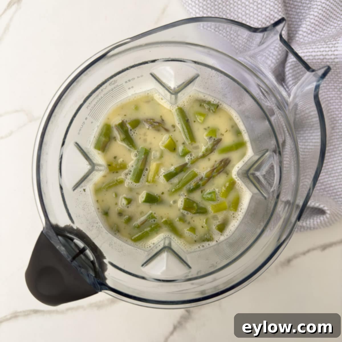 Cooked asparagus with liquids ready for pureeing in a high-speed blender.
