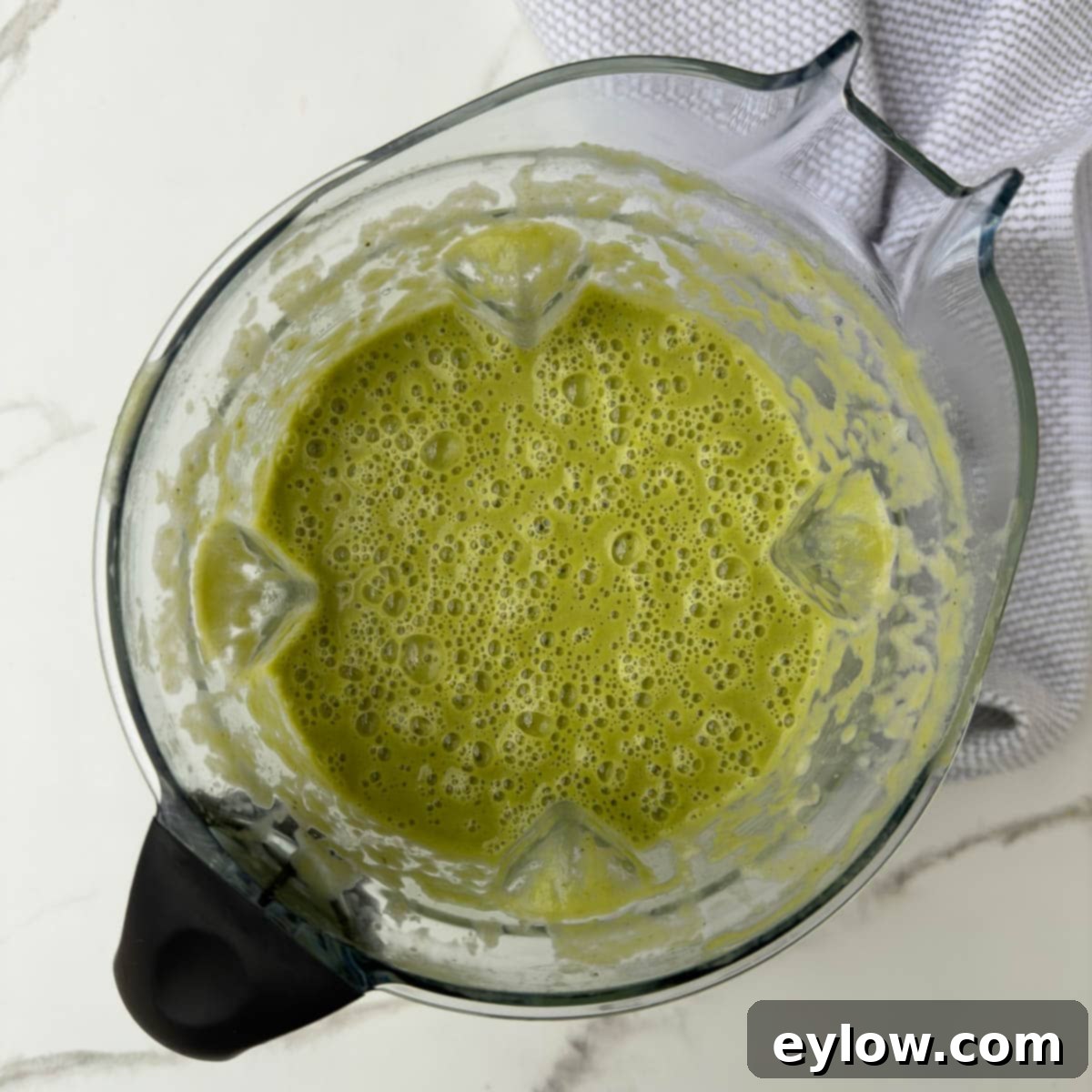 Bright green asparagus soup pureed in a blender container, showing its smooth, ready-to-serve texture.