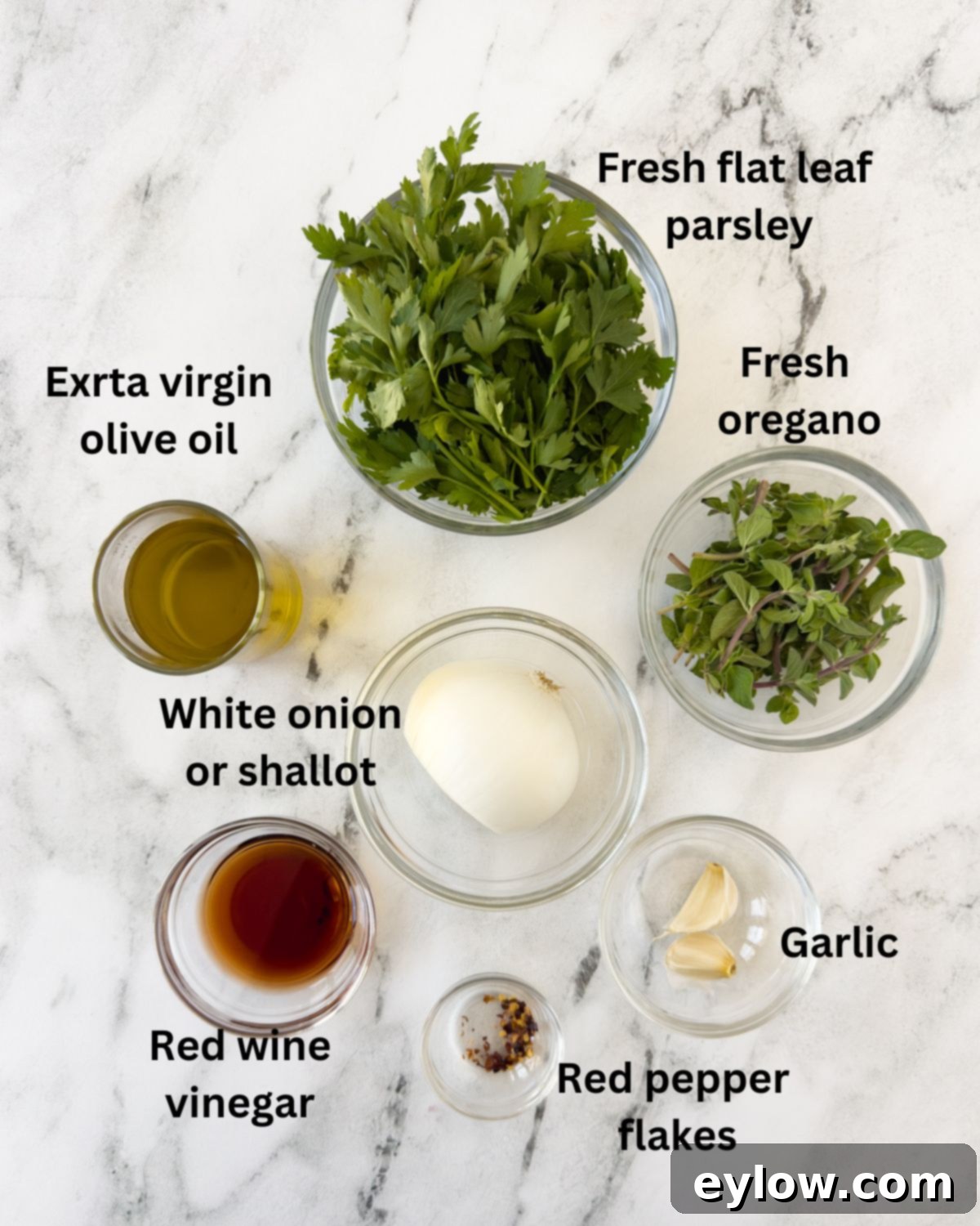 Authentic Argentinian Chimichurri Sauce 3 Ingredients for chimichurri sauce in prep bowls on marble counter, showing fresh parsley, oregano, garlic, onion, and spices.