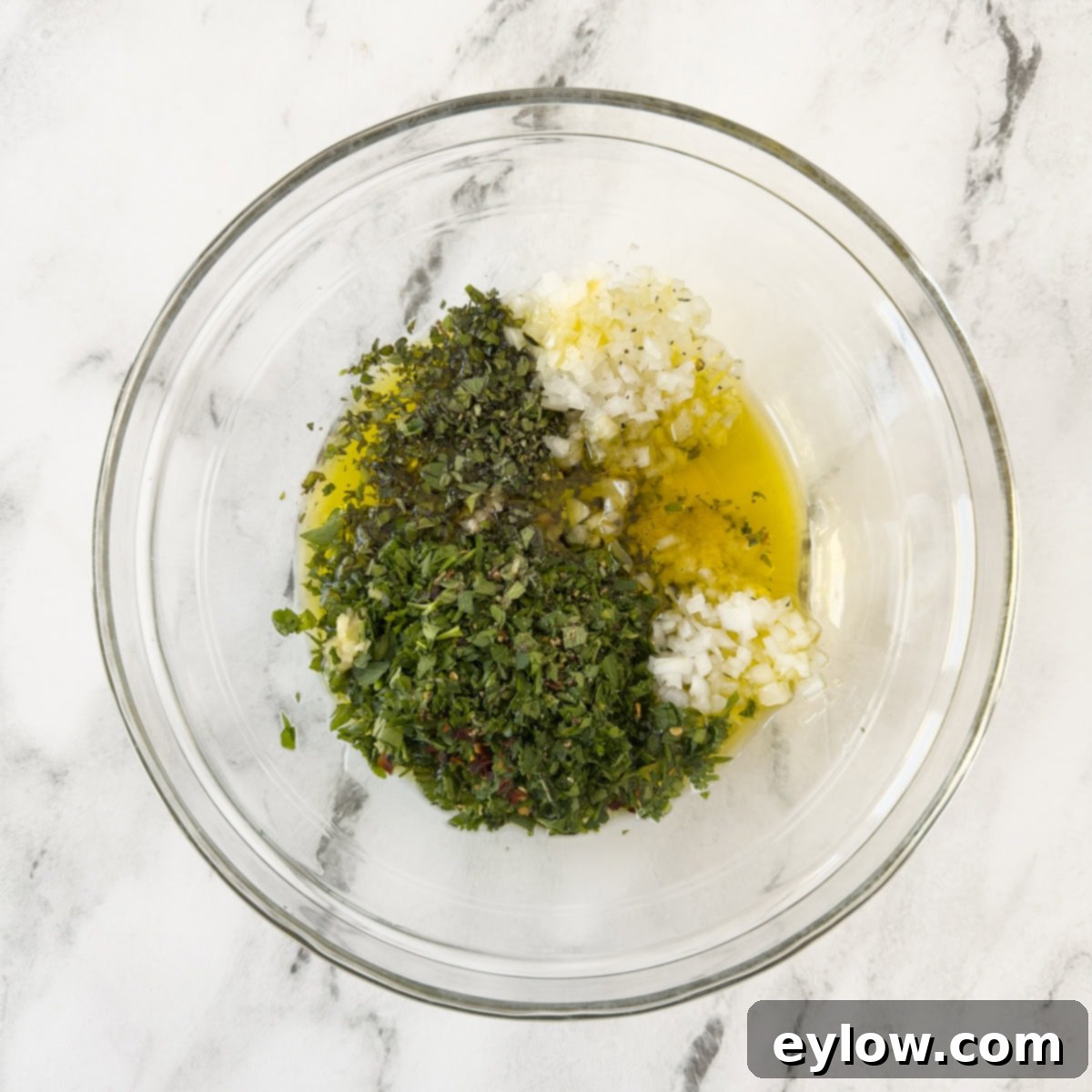Authentic Argentinian Chimichurri Sauce 4 Finely chopped ingredients for salsa chimichurri in a glass bowl, ready to be mixed.