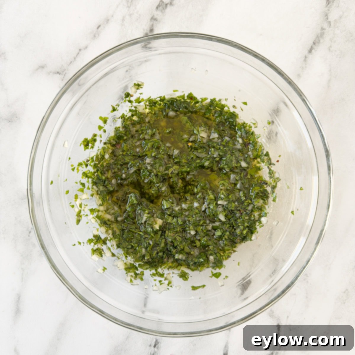 Authentic Argentinian Chimichurri Sauce 5 Chimichurri herb sauce mixed thoroughly in a bowl on the counter, showcasing its vibrant green color, ready to be served.