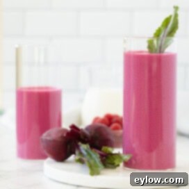 Beautiful bright pink red beet smoothies in tall glasses with red beets on the side.