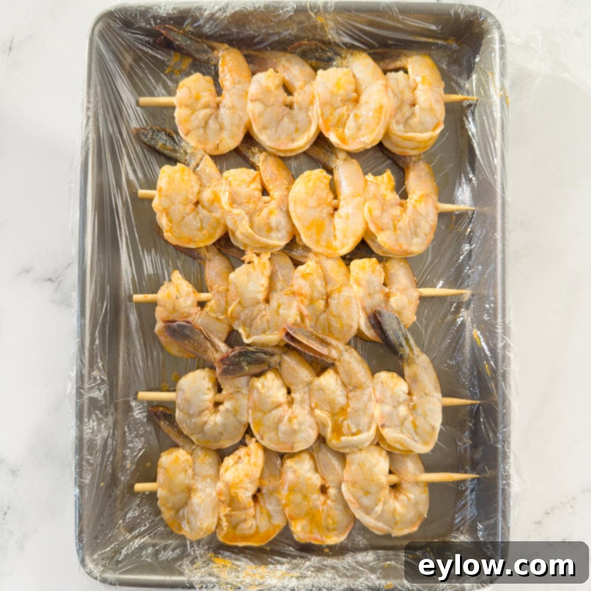 Marinated shrimp threaded onto bamboo skewers for grilling. 