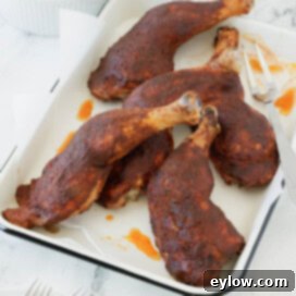 Whole smoked chicken legs in dry rub and bbq sauce on a white tray.