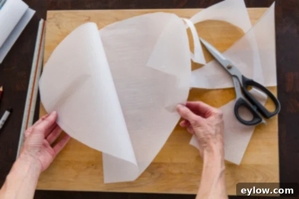 Cutting a half-heart shape from folded parchment paper
