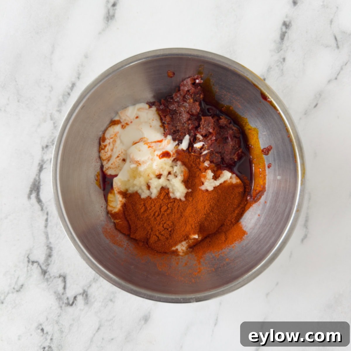 Making harissa aioli, a chili sauce, in a stainless steel bowl.