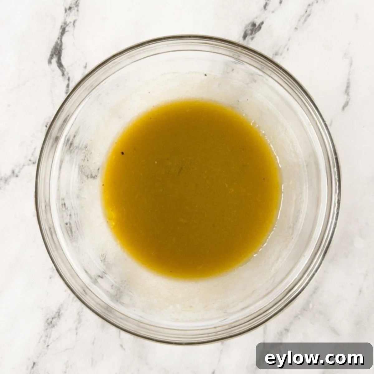A perfectly smooth and emulsified vinaigrette dressing, beautifully blended in a clear glass bowl, showcasing its creamy texture and readiness for use.