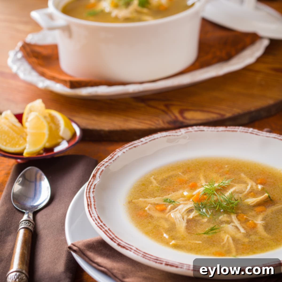 A bowl of chicken rice soup with herbs in a white bowl.