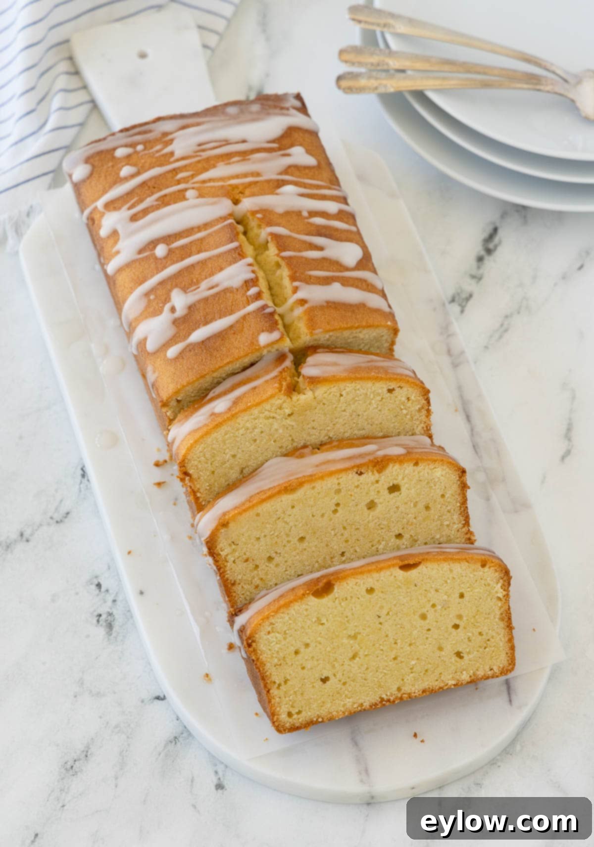 Artisan Gluten-Free Cream Cheese Pound Cake 2 Golden sliced pound cake on a white marble board with dessert plates and forks.