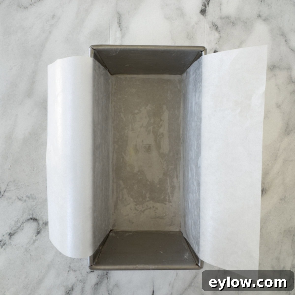 Artisan Gluten-Free Cream Cheese Pound Cake 5 Parchment paper lining a loaf pan with parchment wings over the sides.