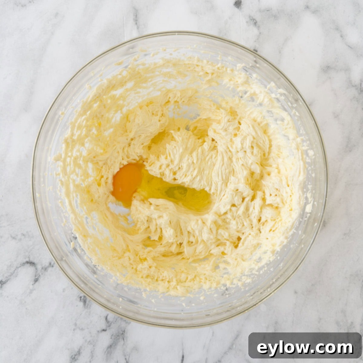Artisan Gluten-Free Cream Cheese Pound Cake 7 Beating eggs into pound cake batter one at a time in a glass bowl.