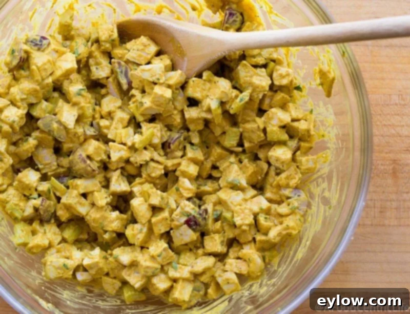 A large bowl filled with golden yellow curried chicken salad, ready to be served or stored.