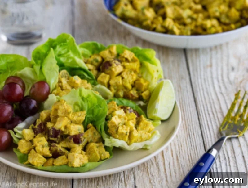 Curried chicken salad elegantly presented on a bed of fresh salad greens, with bright red grapes.