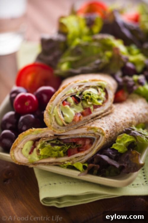 Creamy Avocado Turkey Wraps 2 Freshly made turkey and avocado wrap cut in half, showcasing its vibrant ingredients.