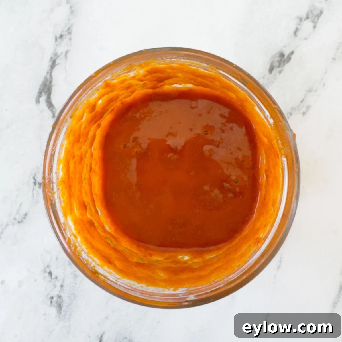 Fiery Harissa Chicken Skewers 4 A glass jar filled with a bright orange-red harissa marinade, showcasing its vibrant color and smooth texture.