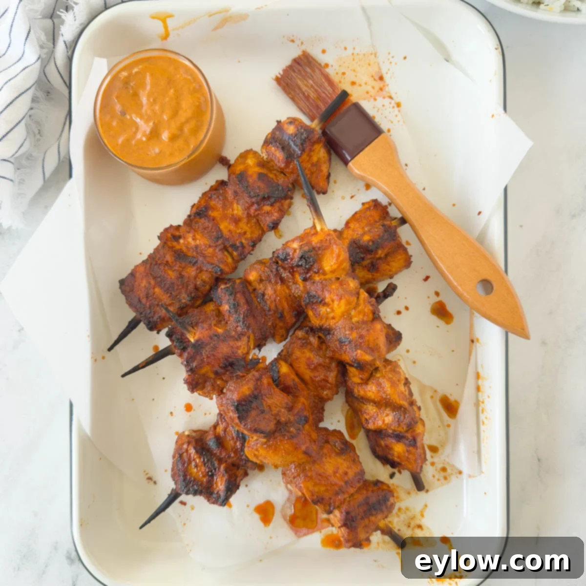 Fiery Harissa Chicken Skewers 8 A tray filled with perfectly grilled harissa chicken skewers, showcasing their vibrant color and slight char, with a small bowl of harissa sauce for dipping.