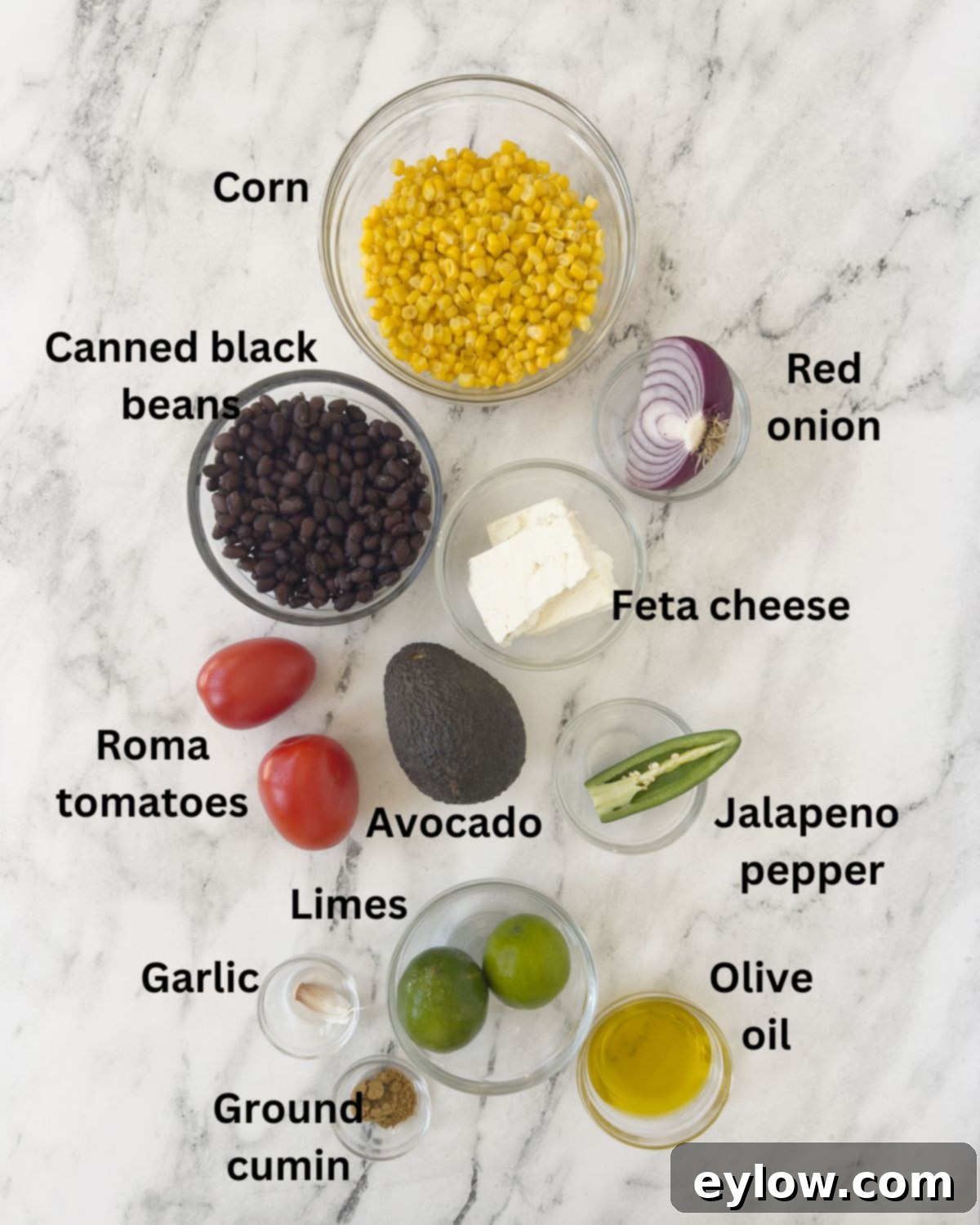 Assorted fresh ingredients for corn, avocado, and black bean salad neatly arranged in individual prep bowls, showcasing vibrant colors and readiness.