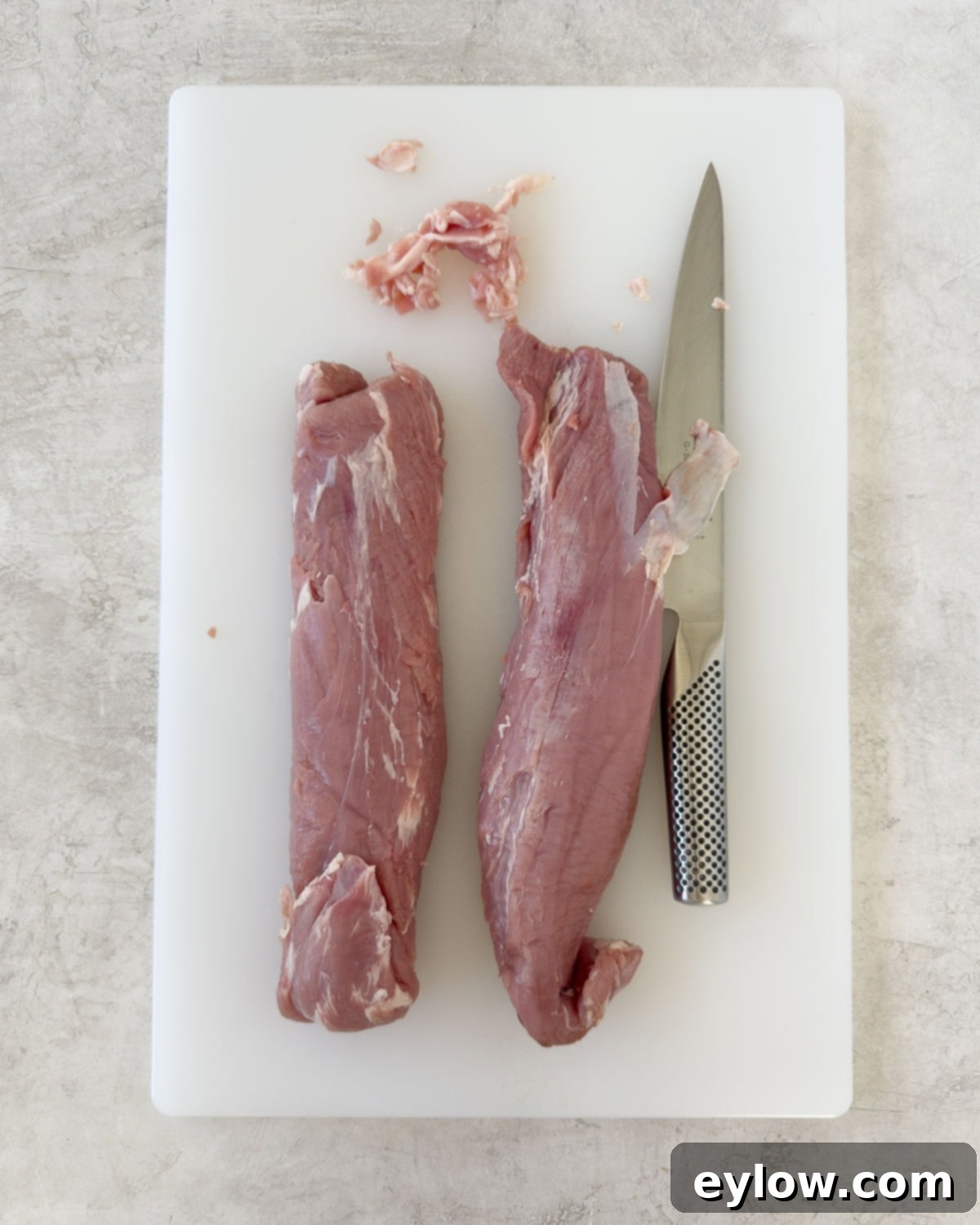 Pellet Grill Smoked Pork Tenderloin 4 Trimming two pork tenderloins of silver skin and excess fat on a cutting board.