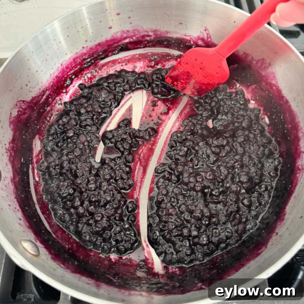 Effortless Blueberry Compote 8 The finished deep purple blueberry compote, perfectly thickened and glistening, viewed in the pan with a spatula, ready to be served.