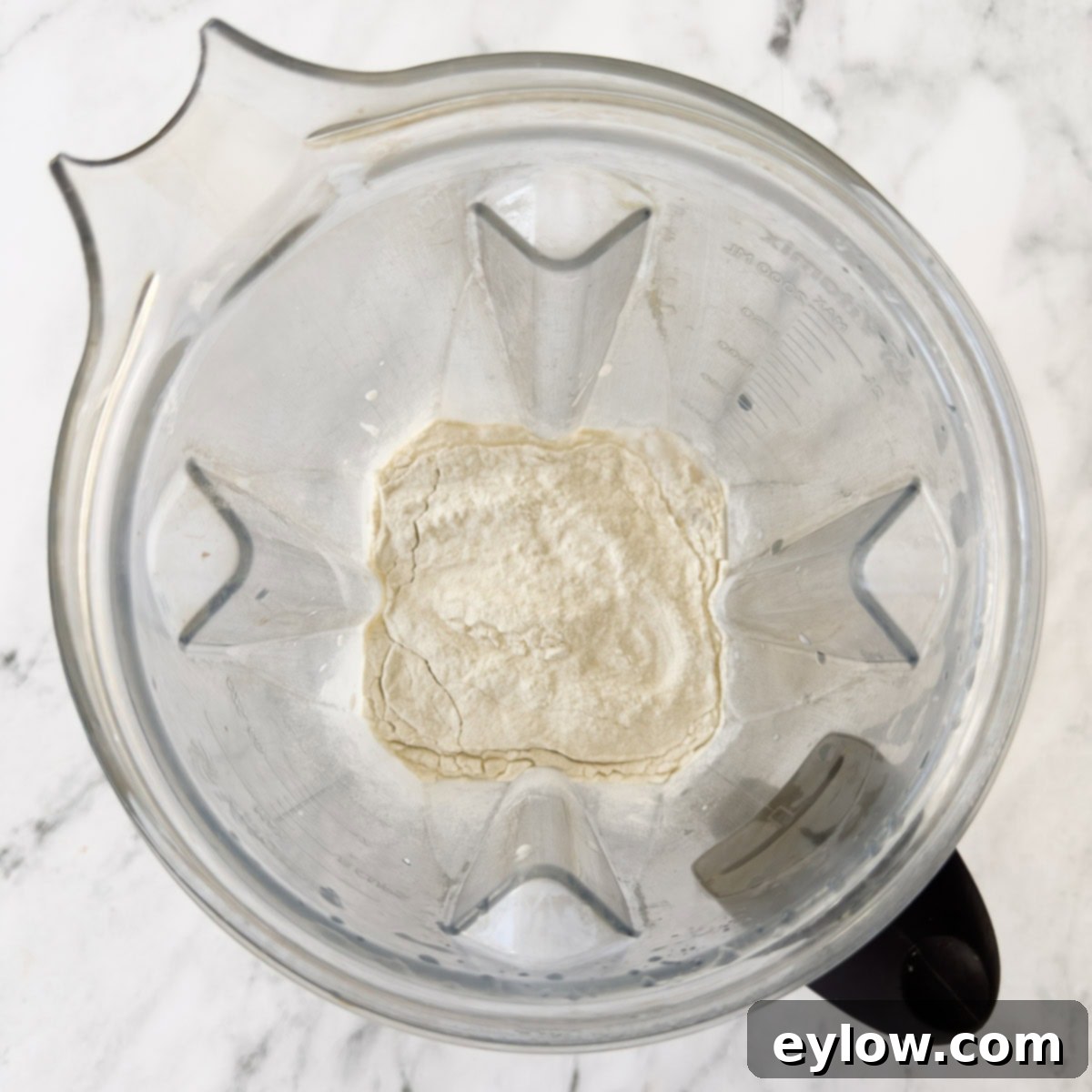 A blender container with milk and protein powder inside.