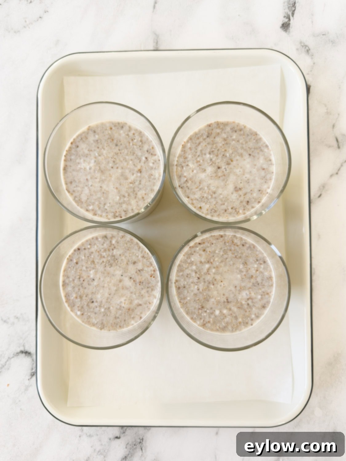 chia seed and coconut milk pudding poured into 4 glasses on a white tray. 