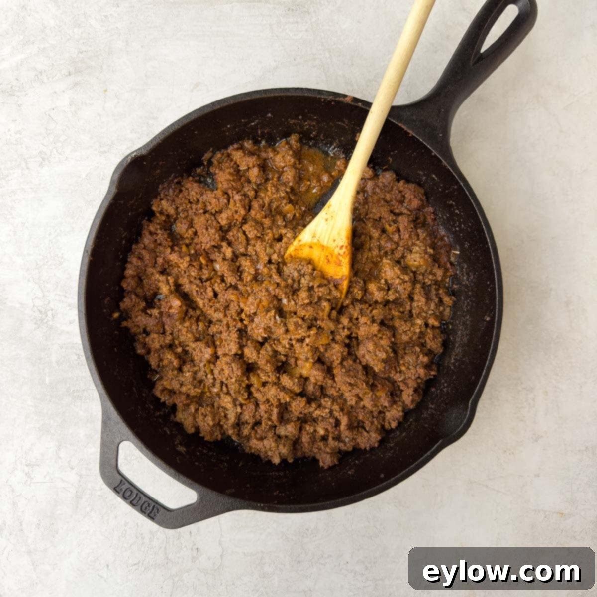 Finished, juicy ground taco meat in a black cast iron skillet, rich brown from the spices and tomato paste.