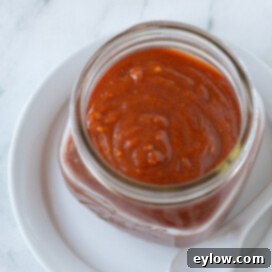 A glass jar of bright red homemade cocktail sauce (seafood sauce).