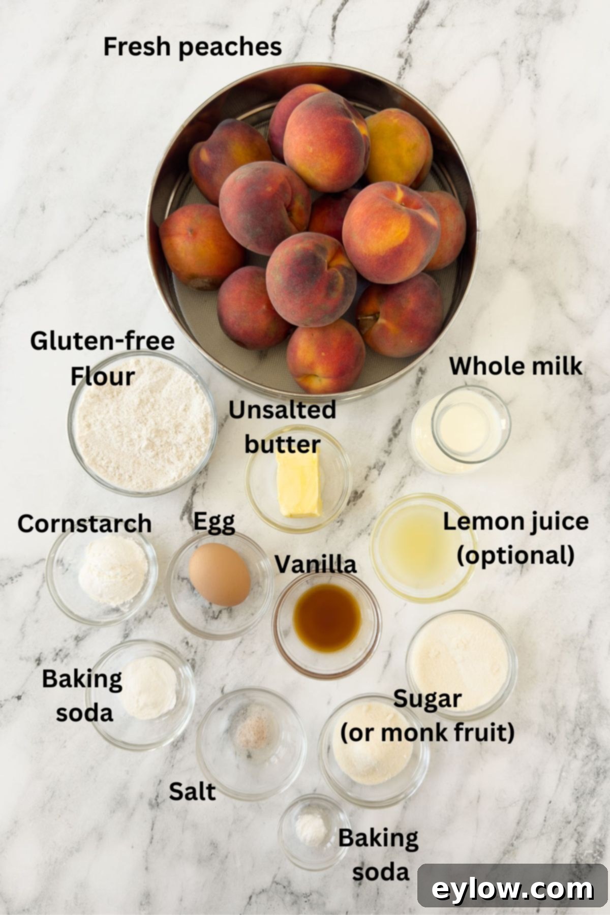 Ingredients for a peach cobbler in prep bowls on a marble counter.