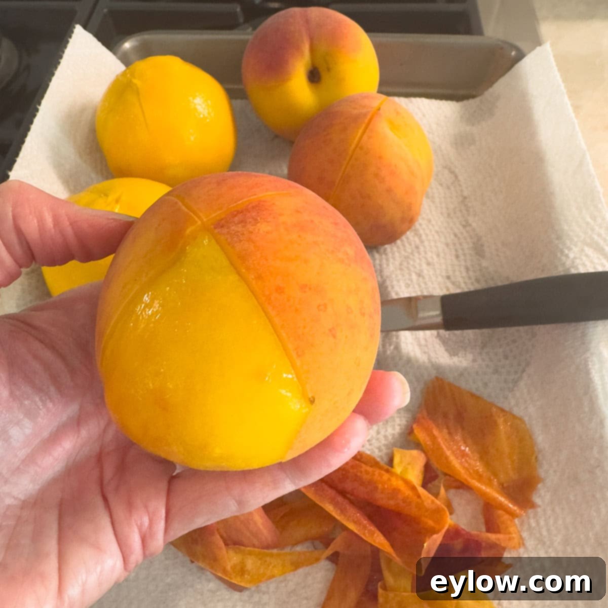 A peeled peach after blanching with peeled peaches in the background.