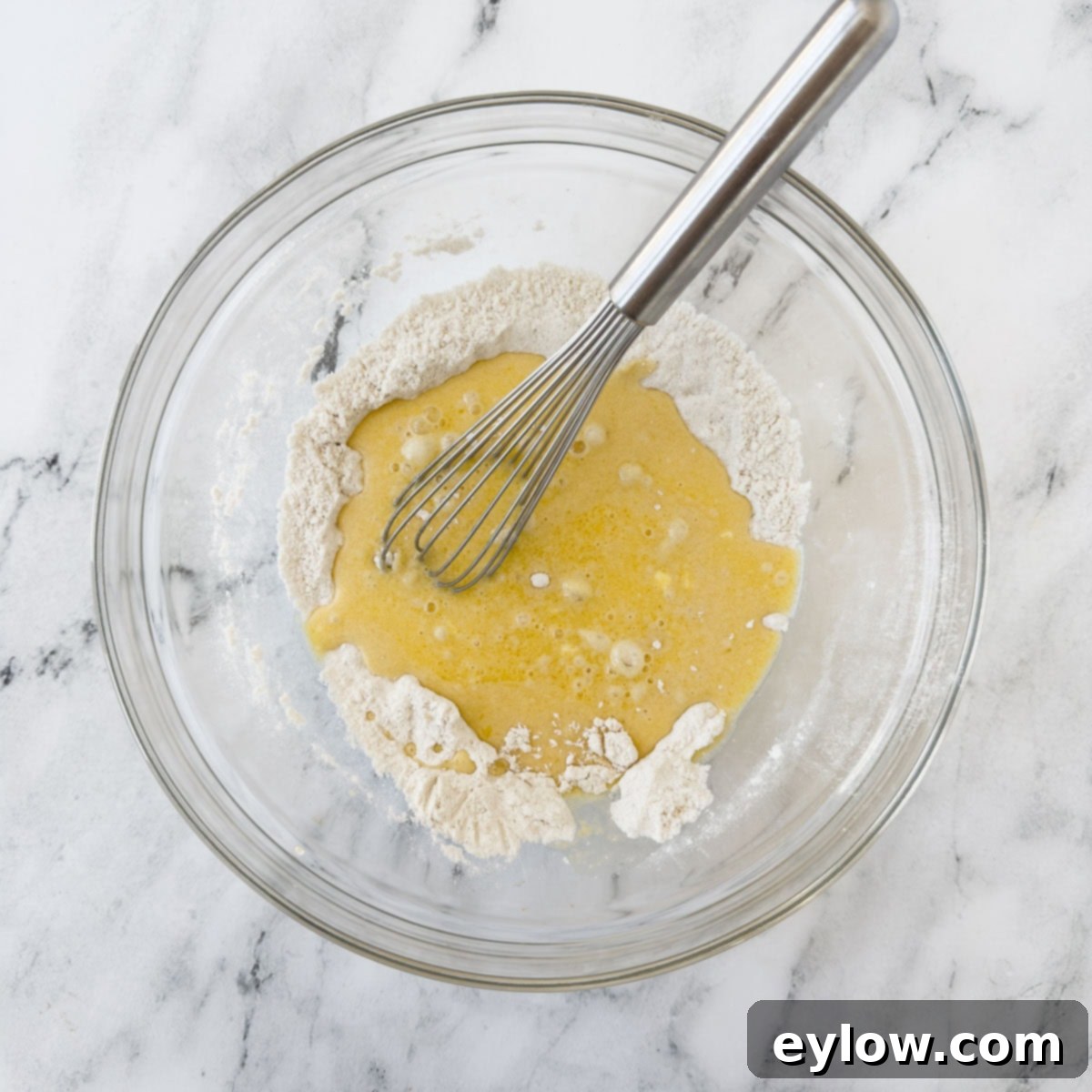 Wet and dry ingredients being whisked together to create a batter.