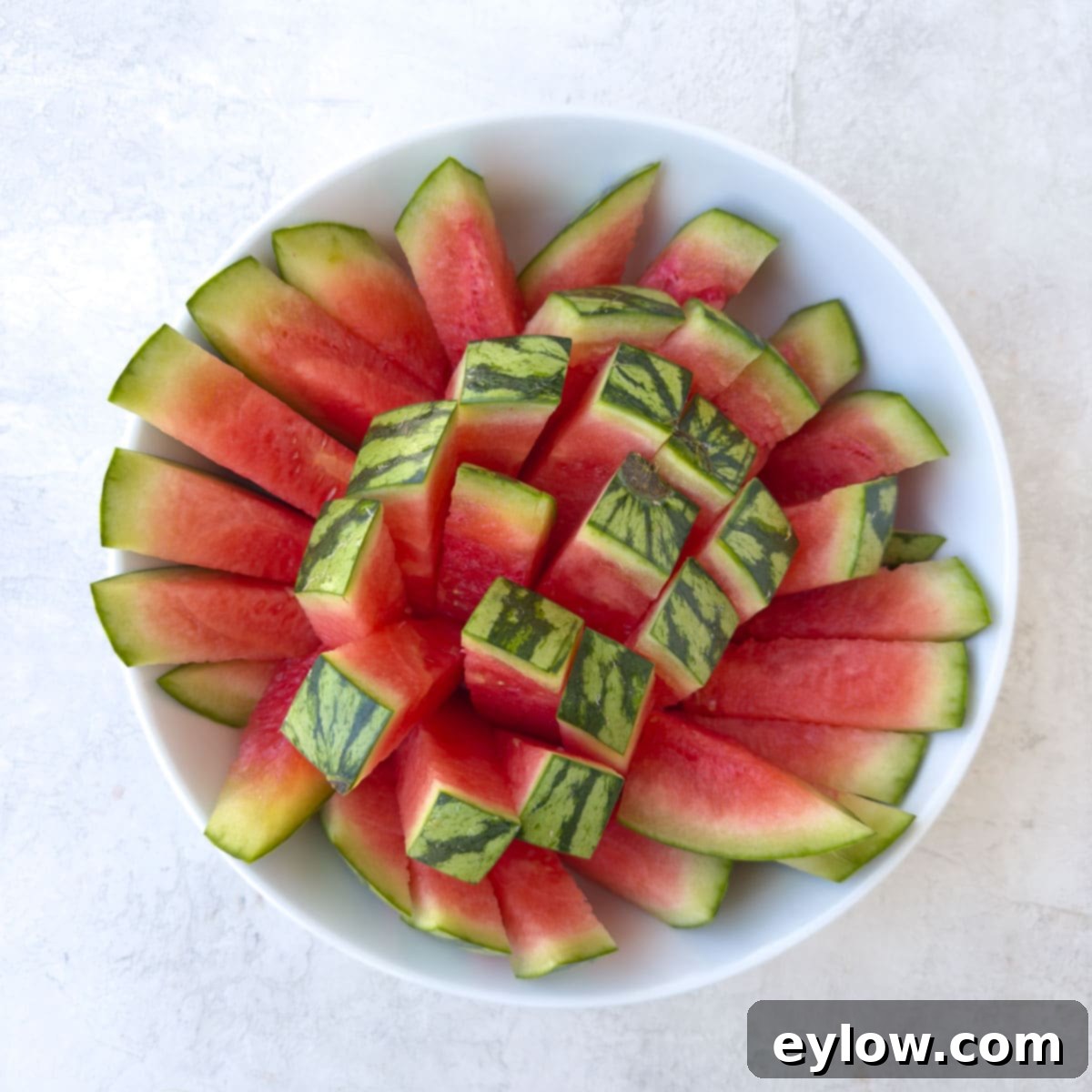 A white bowl of red watermelon sticks ready to serve.