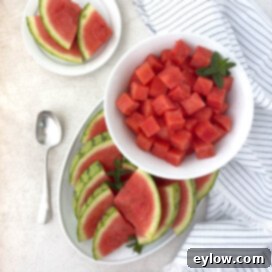A white platter of watermelon slices and a bowl of cubes.
