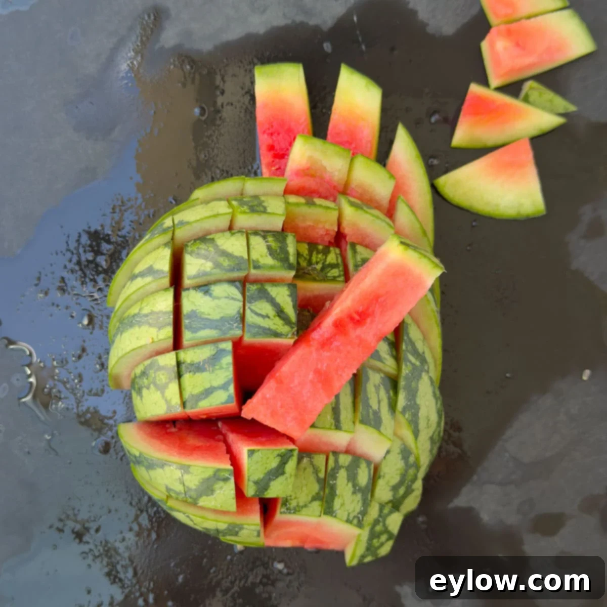 Red watermelon sticks on a black cutting board.