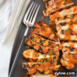 Zesty Grilled Buffalo Chicken 9 Bright red orange Buffalo grilled chicken breasts on a gray platter with a serving fork.