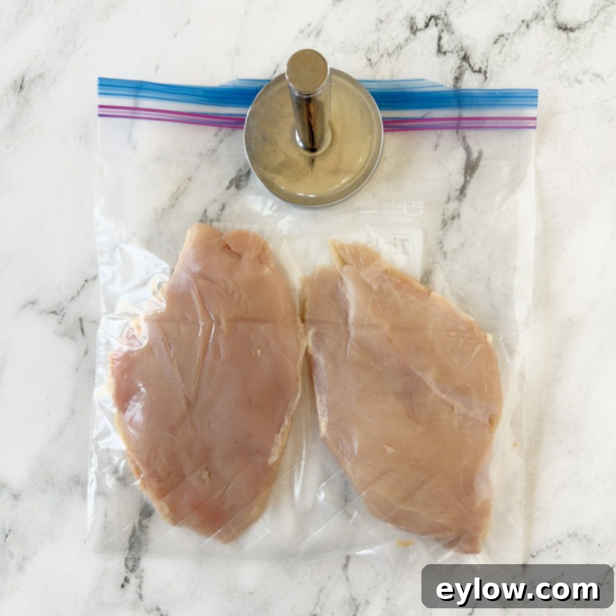 Zesty Grilled Buffalo Chicken 4 Two boneless skinless chicken breasts pounded thin in a zip bag with a meat pounder on top.