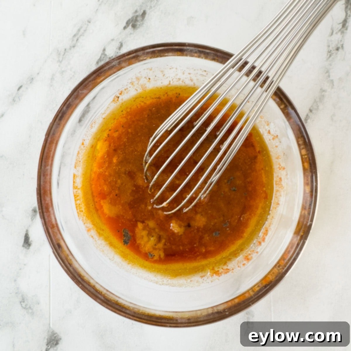 Zesty Grilled Buffalo Chicken 5 A bright orange red buffalo chicken marinade in a small bowl with a whisk.