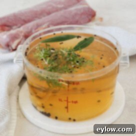 A container of golden brine with herbs, and garlic for brining pork.