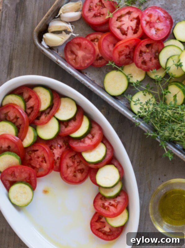 tomato zucchini casserole | AFoodCentricLife.com Sliced Roma tomatoes and zucchini are meticulously layered in an oval baking dish, ready for the oven to become a delicious casserole.