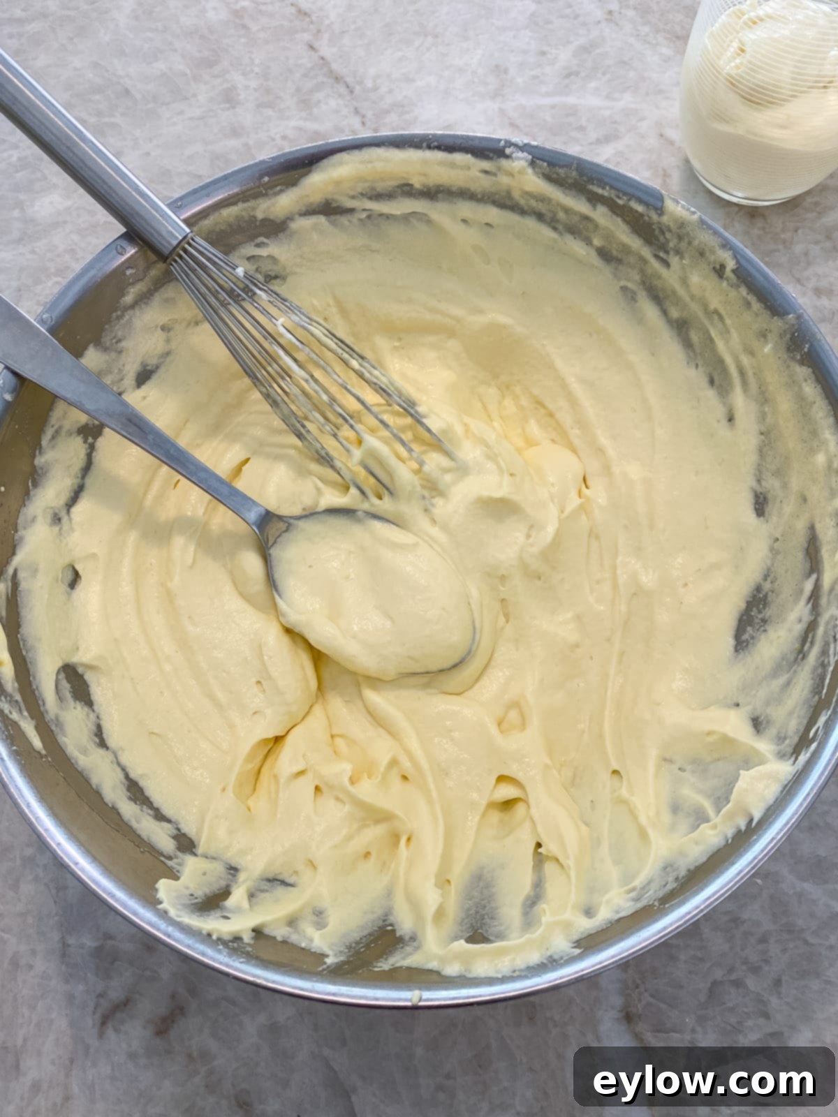 Whip Up Luscious Lemon Mousse 3 A large stainless steel bowl containing whipped and blended mousse, with a whisk and spoon resting beside it, showcasing the light texture.