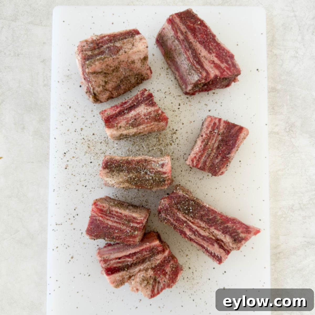 Rich Braised Beef Short Rib Ragu 4 Salt and pepper seasoned beef short ribs on a white cutting board.