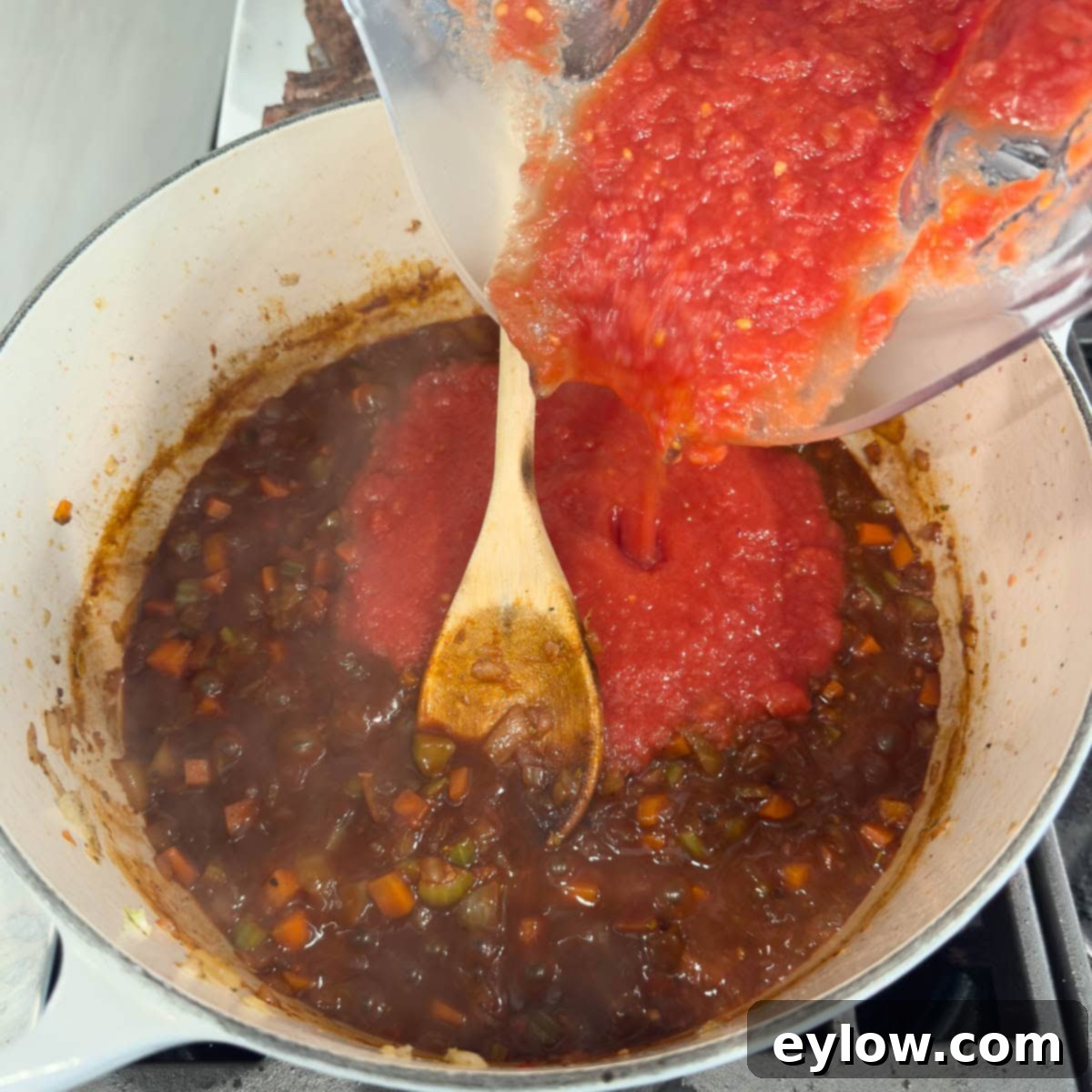 Rich Braised Beef Short Rib Ragu 9 Bright red pureed tomatoes being poured into a pot.