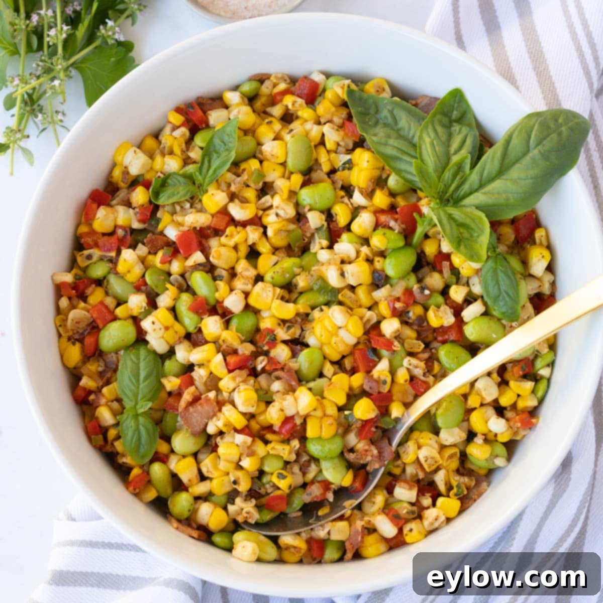 Closeup of corn succotash with red and green peppers, edamame and bacon.