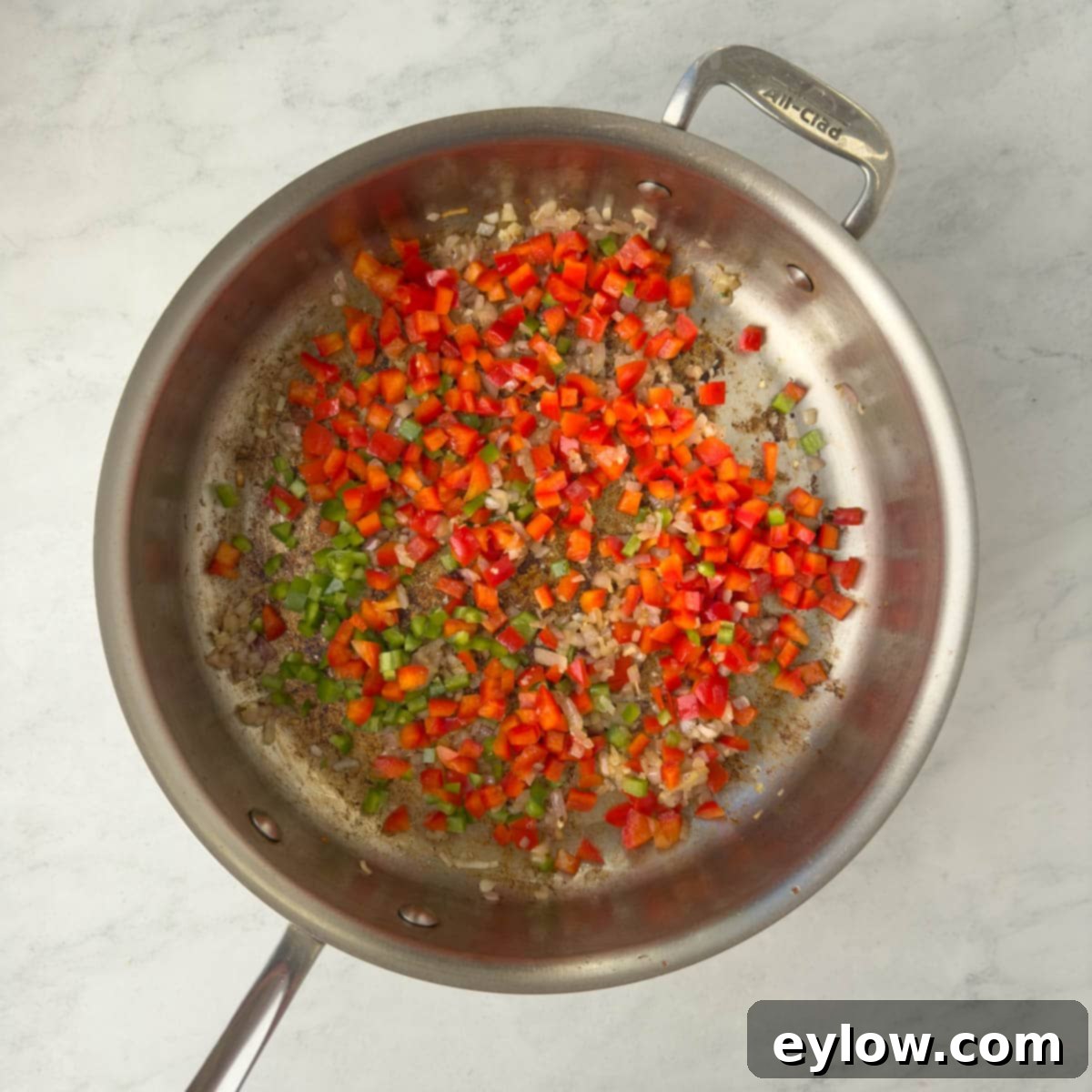 Sautéing red and green pepper in a saute pan.