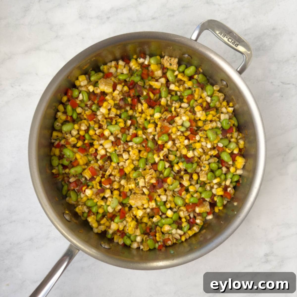 Colorful corn, red and green peppers and bacon in a saute pan.