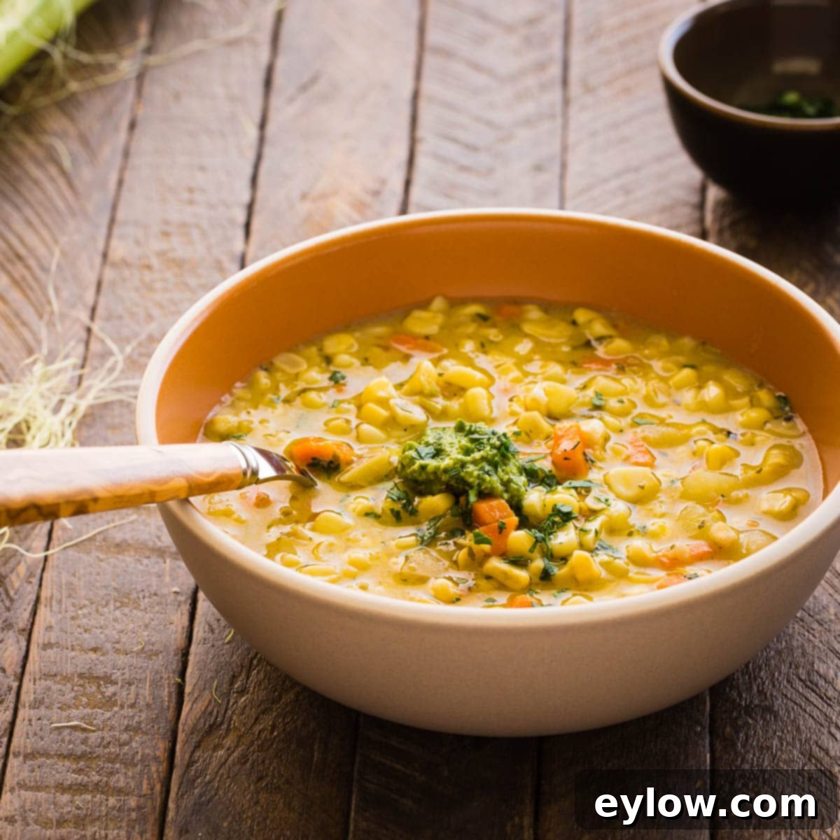 Creamy Dairy-Free Potato Corn Chowder 4 A single bowl of creamy corn chowder with fresh herbs for garnish, with a wood handled spoon.