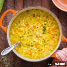 Creamy Dairy-Free Potato Corn Chowder 5 An orange dutch oven with bright yellow corn and potato chowder, a hearty and comforting soup.