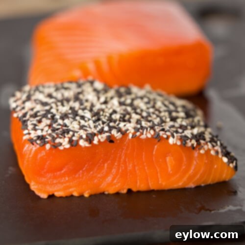 Coating bright orange salmon filets with sesame seeds for a crusted top.