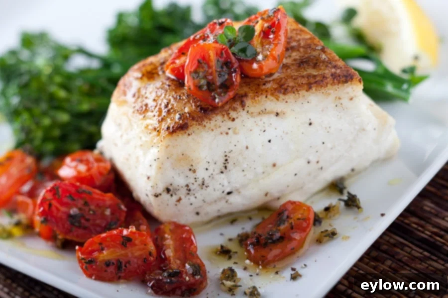 Halibut searing in a non-stick pan, developing a golden crust.